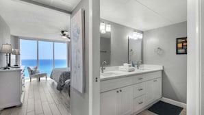 Une salle de bain moderne dotée d’un grand miroir, de deux vasques et offrant une vue sur l’océan.