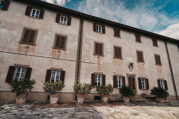 Un bâtiment doté de nombreuses fenêtres et portes, avec des plantes en pot devant et un sol pavé.