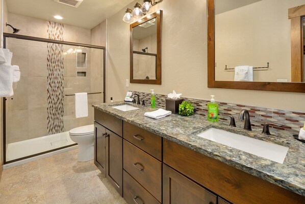 A modern bathroom with a glass-enclosed shower, a double sink vanity, and a large mirror.