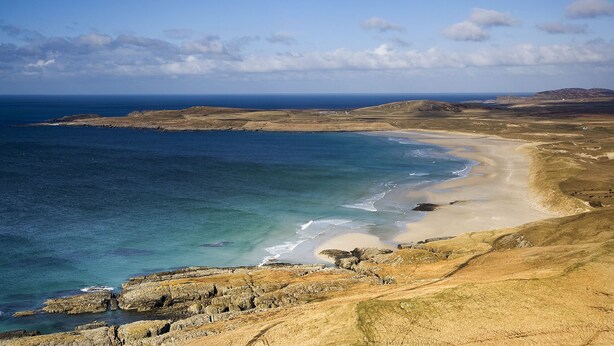 Eine Küstenlandschaft mit Sandstrand, felsigen Klippen und freiem Blick auf den Ozean.