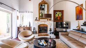 A living room with a fireplace, a sofa, a round coffee table, and a television. - La Villa des Amoureux, charm in Drôme Provençale, with secured swimming pool (Clansayes)
