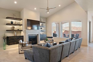 A spacious living room with a fireplace, a sofa set, and a TV mounted on the wall. - Arcadia 27 | STEPS to the pool * Red Mountain Views * Sleeps 19 (Santa Clara)