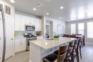 Enjoy cooking in this kitchen with a central island, bar stools, white cabinetry, and stainless steel appliances.