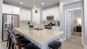 A modern kitchen with white cabinets, stainless steel appliances, and a central island with seating. - Arcade Adventure, LOADED WITH EXTRAS, Come Play! (Washington)