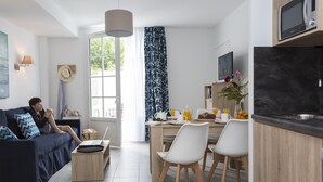 Una sala moderna con un sofá, una mesa de centro y una zona de comedor con sillas y una mesa.