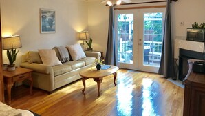 A living room with a sofa, coffee table, and a ceiling fan. There is a sliding glass door leading to an outdoor patio area. - Quiet, comfortable home. Near Intel and Nike campuses. (Hillsboro)