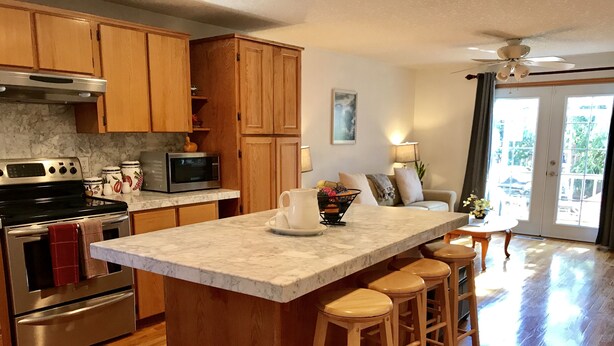 A kitchen with wooden cabinets, a marble countertop, a built-in oven, a microwave, and a large island with stools. - Quiet, comfortable home. Near Intel and Nike campuses. (Hillsboro)