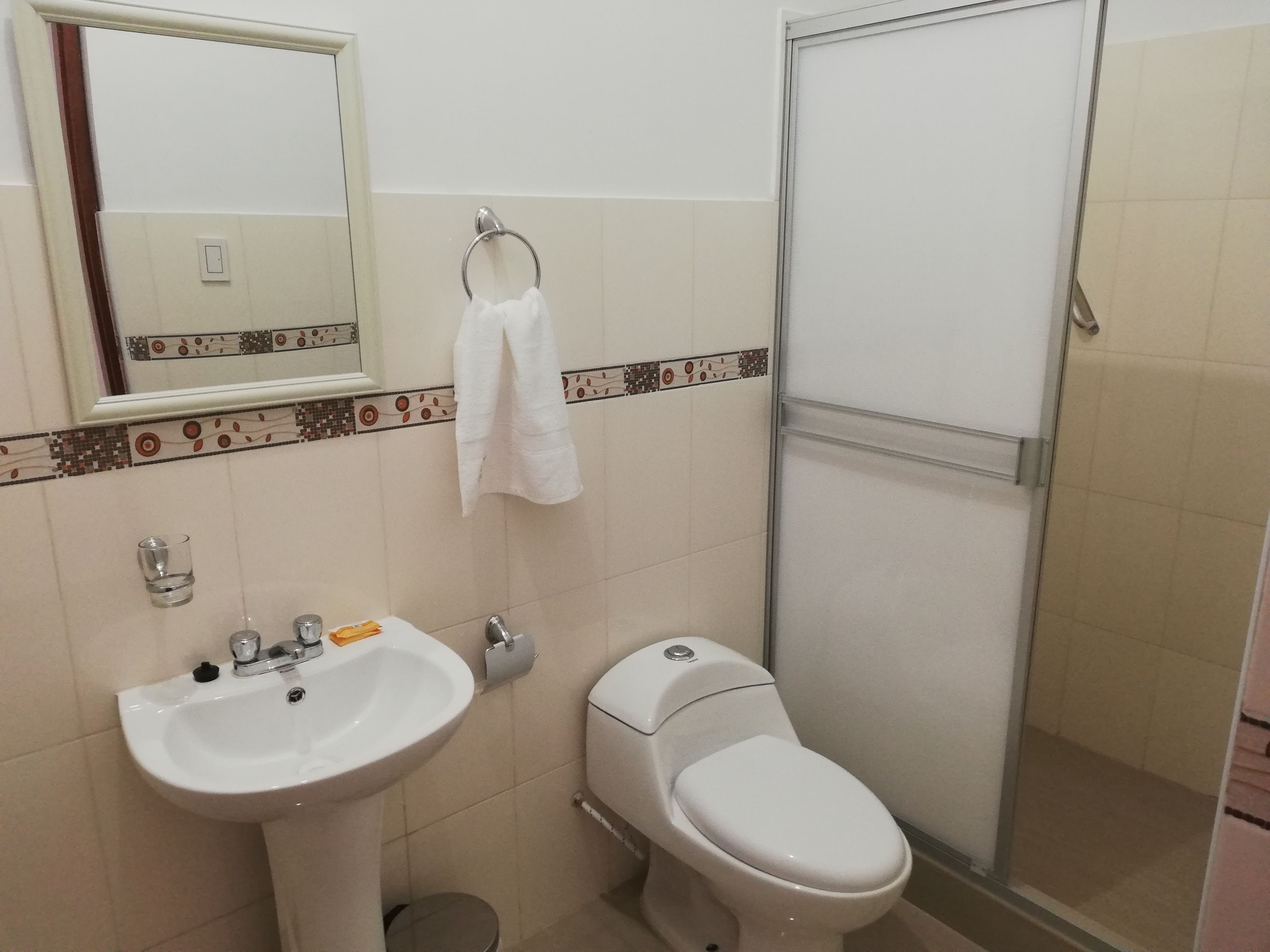 Un baño con lavamanos, inodoro y cabina de ducha de vidrio.