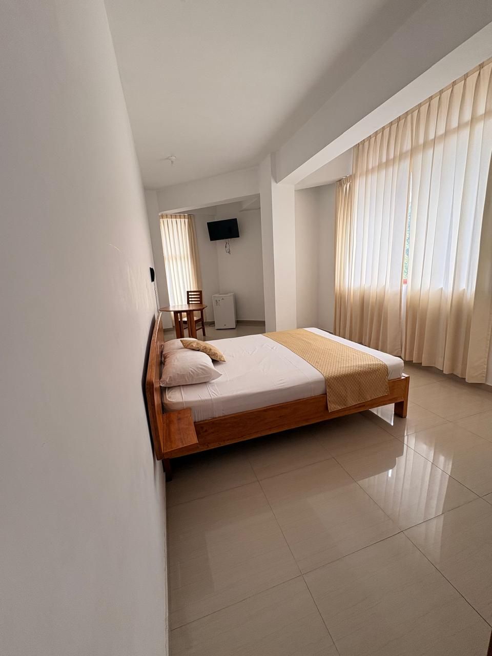 Une chambre à coucher avec un lit, une chaise, un bureau et un téléviseur.