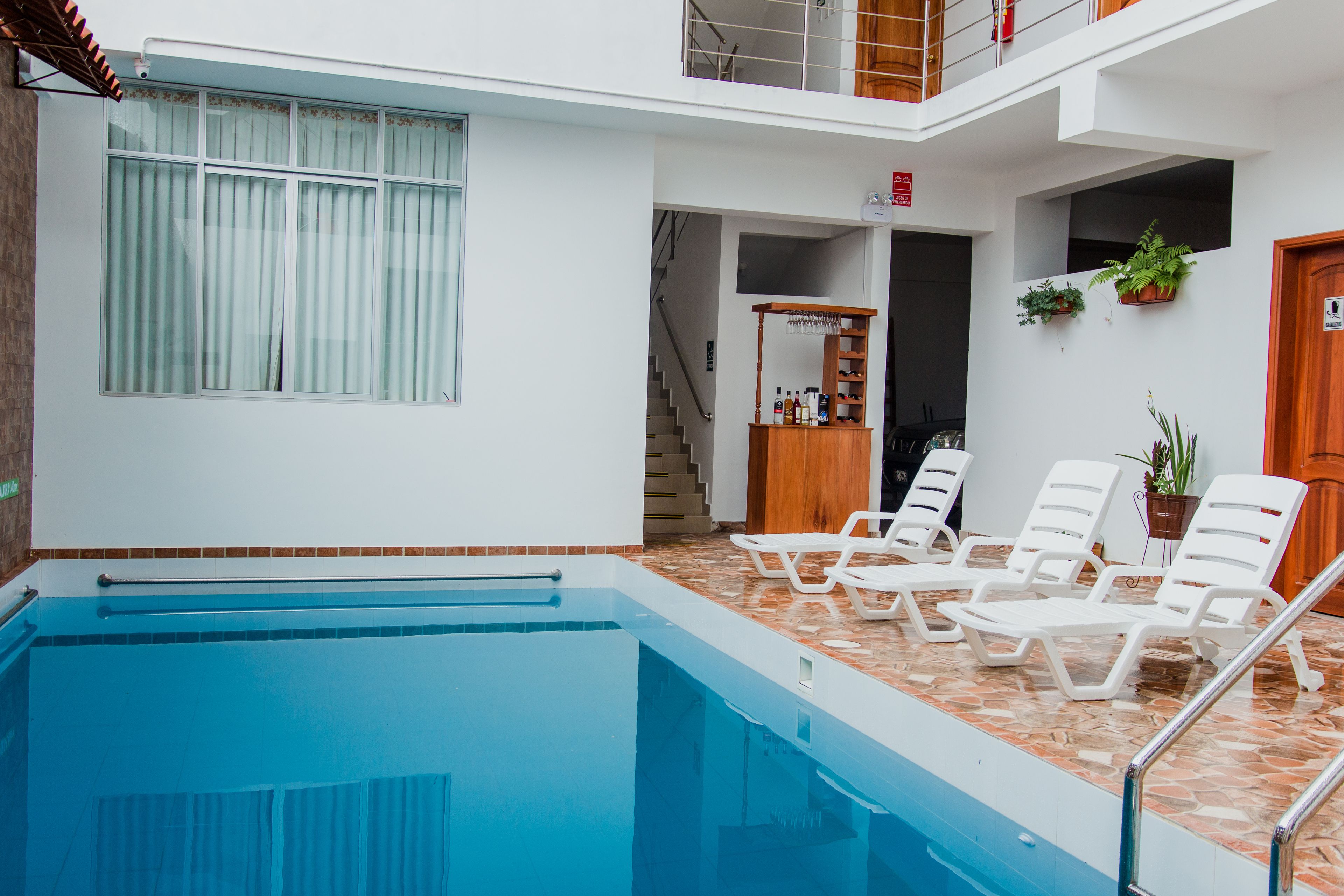 Una piscina con sillas de descanso, una escalera de madera y plantas en macetas.