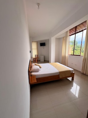A bedroom with a bed, a desk, a chair, and a TV. - Posada del Ángel Hotel (Tarapoto)
