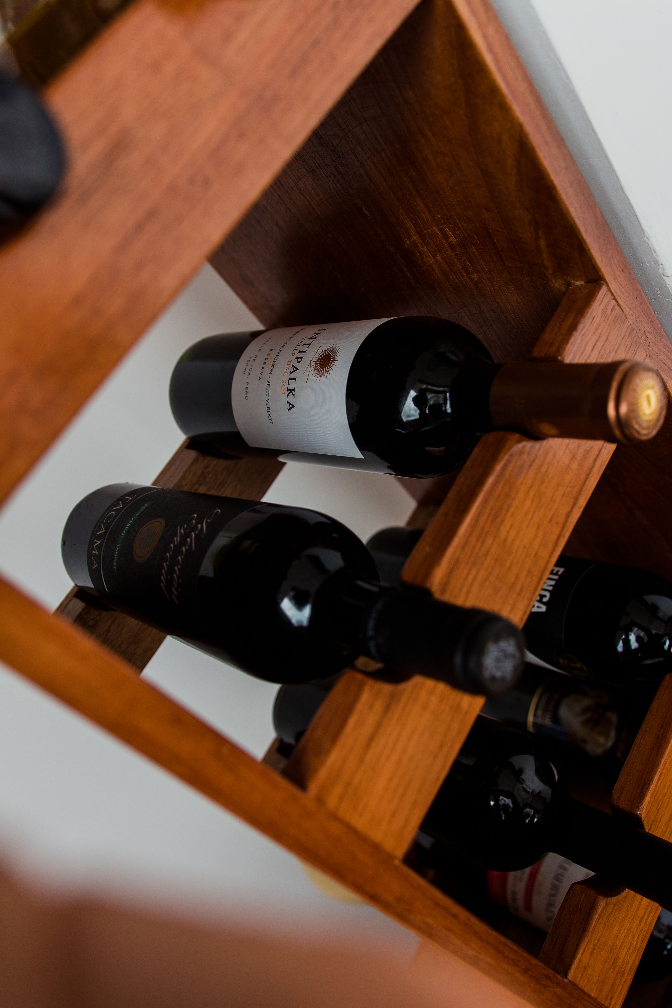 A wooden wine rack with several bottles of wine.