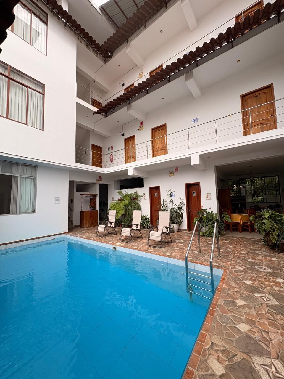 A multi-level indoor pool area with a clear blue pool, multiple seating areas, and a staircase leading to upper levels.