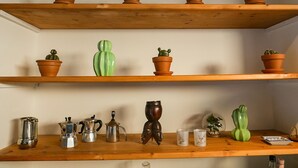 A wooden shelf with terracotta pots and various kitchen items.