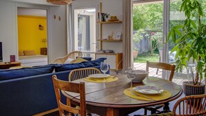 A dining area with a round wooden table, chairs, and a view of the outdoors.