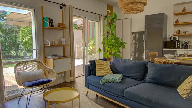 A modern living room with a sofa, a chair, a table, and a hanging plant.