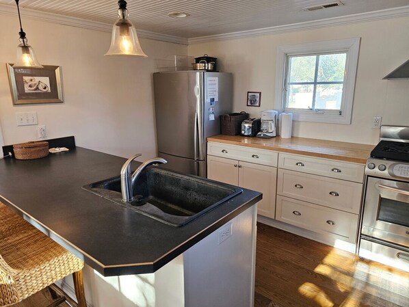 A kitchen with a large island, stainless steel appliances, and a window providing natural light.