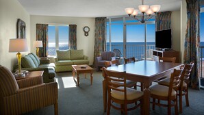 Ein Hotelzimmer mit Essbereich, einer Sitzecke, einem Fernseher und Meerblick.