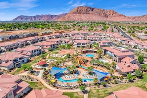 A resort with multiple buildings, a central pool area, and a mountainous backdrop.