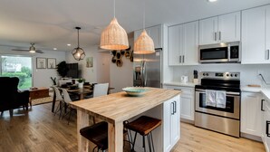 A modern kitchen with white cabinets, stainless steel appliances, and a wooden island with stools. - Scottsdale Chic Condo w/ Heated Pool, Walk Everywhere! A+ LUXURY in Old Town (Scottsdale)