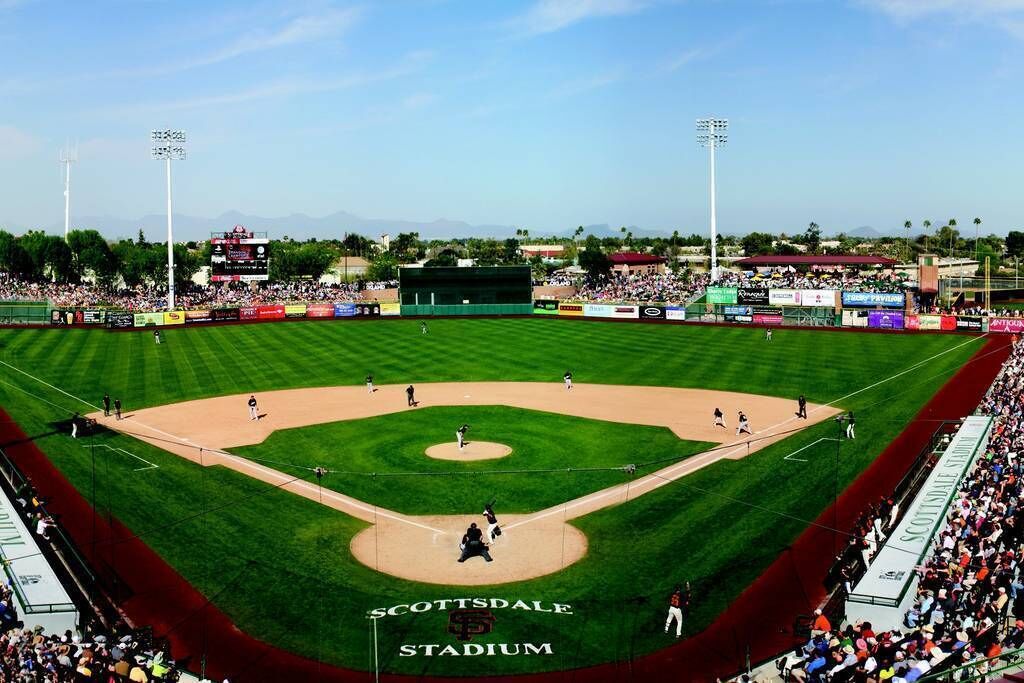 A baseball stadium with a well-maintained field, seating for spectators, and a scoreboard.