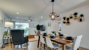 A modern dining area with a wooden table, white and gray chairs, and a hexagonal ceiling light fixture. - Scottsdale Chic Condo w/ Heated Pool, Walk Everywhere! A+ LUXURY in Old Town (Scottsdale)