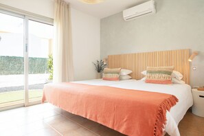 Een hotelkamer met een bed, een raam met gordijnen, een airconditioning en een nachtkastje met een lamp.