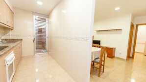A kitchen with a countertop, sink, and oven. There is a dining area with a table and chairs. - Ermitana 2º-B (Peñiscola)
