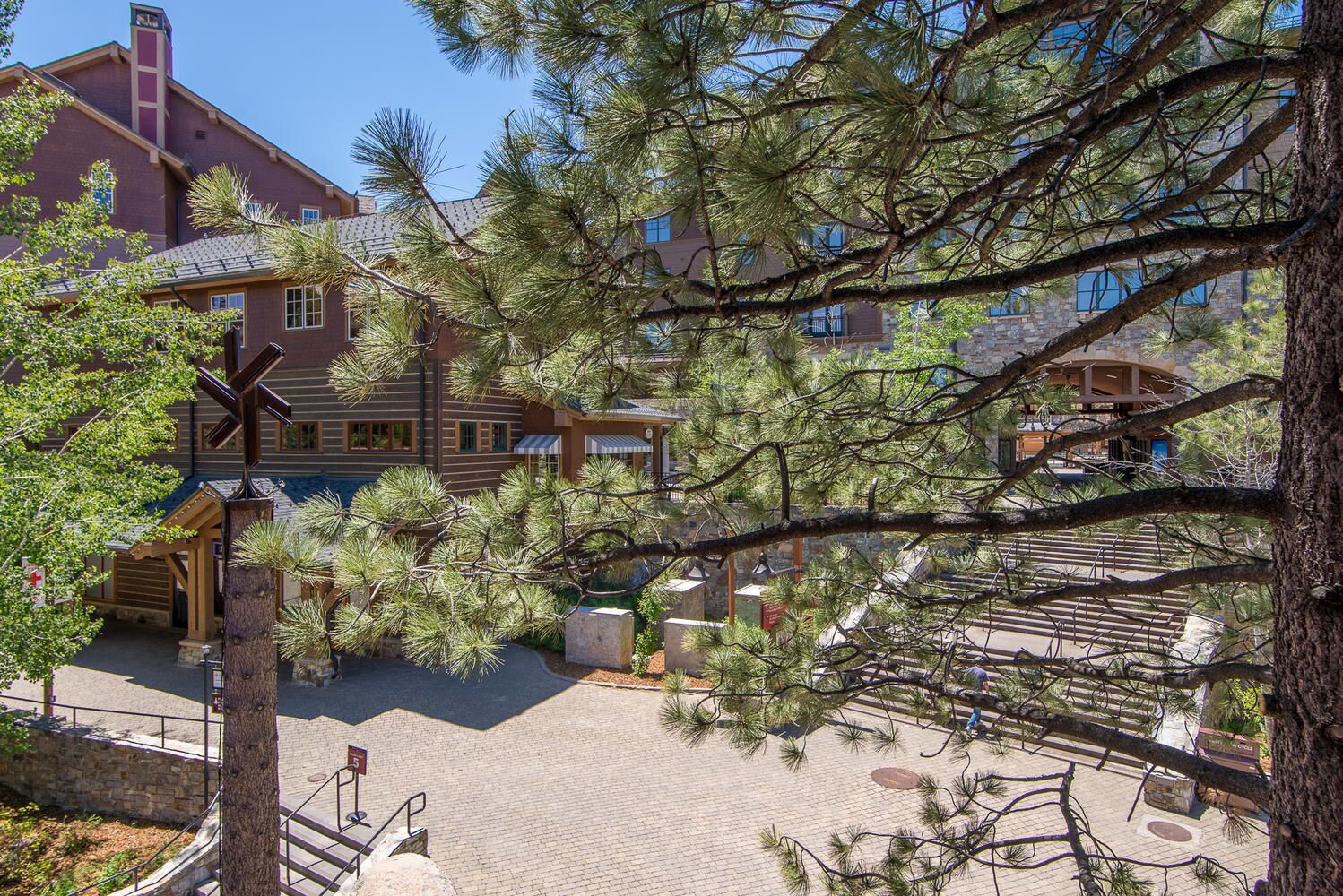 A hotel with a stone facade, multiple stories, and a central courtyard with pine trees.