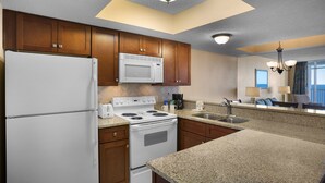 Una cocina moderna con armarios de madera, un refrigerador blanco, un microondas, una estufa y un fregadero.