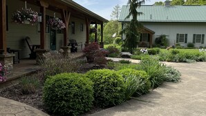 Un bâtiment doté d’un porche abrité et d’un jardin agrémenté de diverses plantes et fleurs.