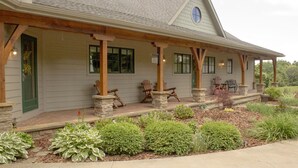 Une maison dotée d’un porche abrité, de piliers en pierre et d’un jardin où poussent différentes espèces de plantes.