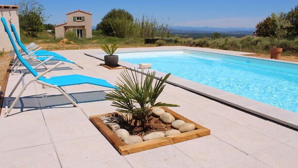 A pool area with lounge chairs and a small garden.