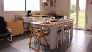 A kitchen with a dining table, chairs, cabinets, and a window.