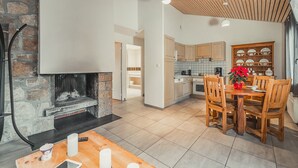 A modern kitchen with a stone fireplace, wooden dining table, and chairs. - Logement 2/4 pers. Premium  - Chanac (Chanac)