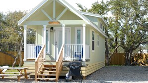 A small, single-story cabin with a porch, a grill, and a picnic table. - White Oak -Beautiful Cottage - Perfect For a  Family Getaway (Aransas Pass)