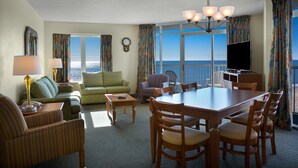 Ein Hotelzimmer mit Essbereich, einer Sitzecke, einem Fernseher und Meerblick.