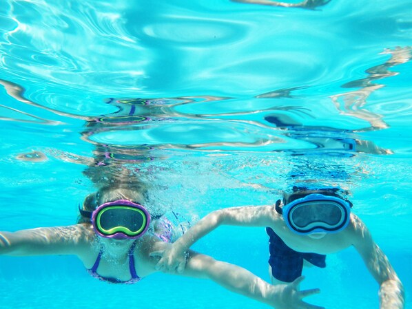 An underwater view of a swimming pool with two people wearing goggles.