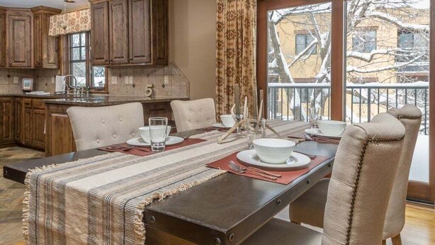 Un comedor con una mesa larga, sillas y vistas a un paisaje nevado a través de amplios ventanales.
