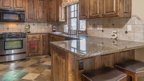 Una cocina con armarios de madera, encimera de granito, estufa de acero inoxidable y ventana con vistas.