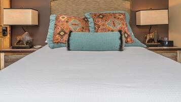 A bed with patterned pillows and a matching throw, flanked by nightstands with lamps and decorative items.