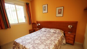 Ein Schlafzimmer mit einem Bett, Nachttischen, einem Holz-Kopfteil und zwei gerahmten Bildern an der Wand.