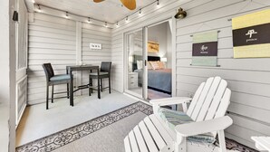 Una habitación acogedora con ventilador de techo, cama, escritorio y sillas, y un ventanal grande.