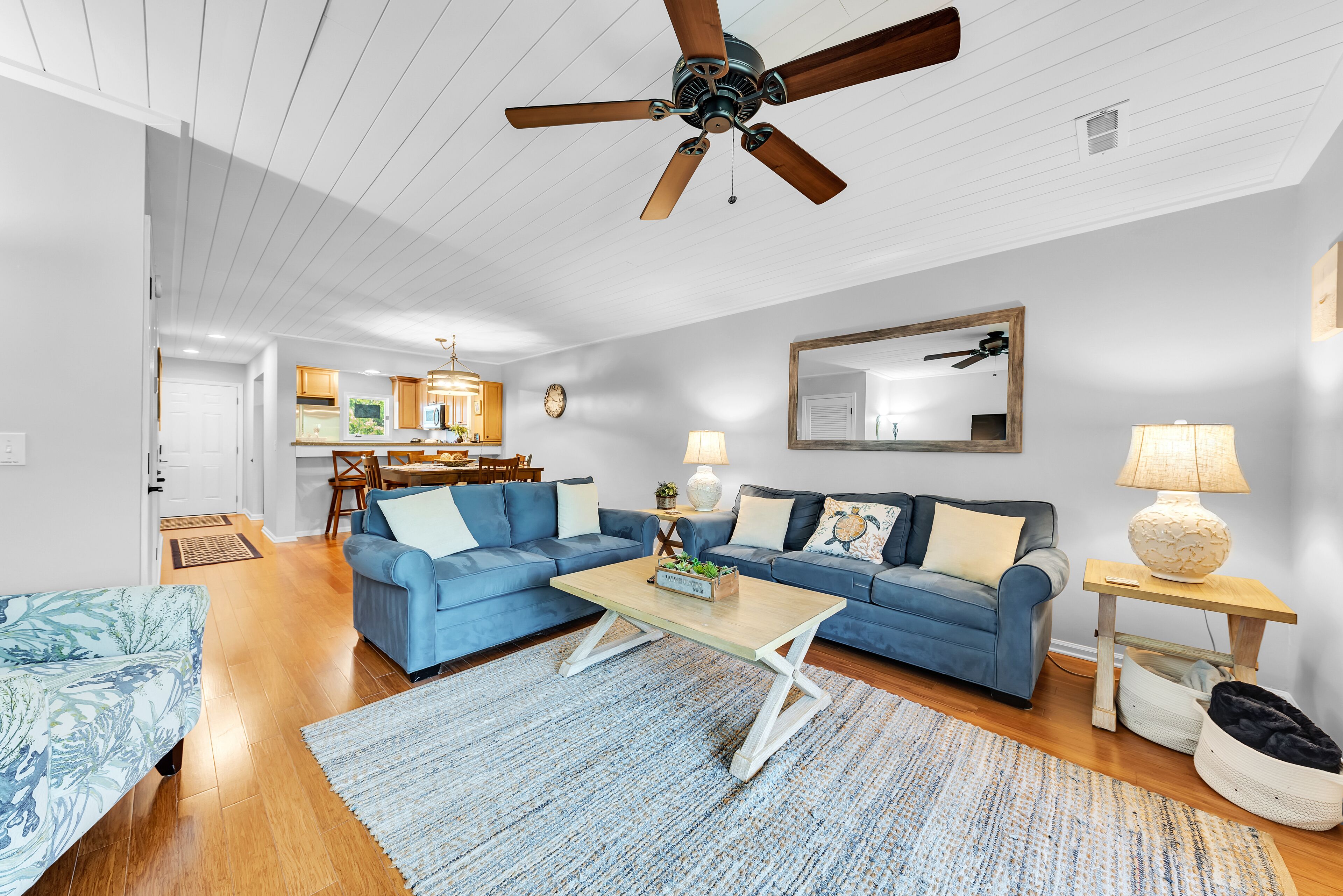 A living room with a blue sofa, a wooden coffee table, and a ceiling fan.