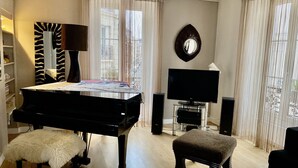 A room with a grand piano, a flat-screen TV, and a mirror on the wall. - PORTE MAILLOT & ETOILE - PERFECT WORK & TOURIST LOCATION - LUX RENOVATED FLAT (Paris-16)