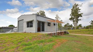 A single-story, metal-framed house with a covered porch and a fenced yard. - Hami's Retreat - Burrum Heads- Close to Boatramp -2BR - Aircon (Burrum Heads)