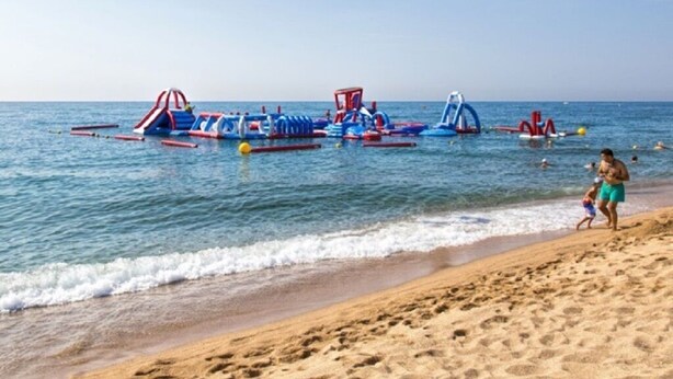 A beach with inflatable water play structures and people walking along the shore. - House with large patio/solarium near the beach, in the center. (Malgrat de Mar)