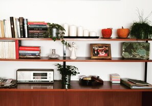 Una estantería con libros, objetos decorativos y una radio antigua.