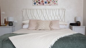 A neatly arranged bedroom with a bed, two bedside tables, and a decorative wall piece. - Large and quiet apartment 20 minutes from Venice (Venezia)