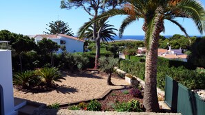 Ett bostadsområde med en sandtäckt innergård, palmer och utsikt över havet.